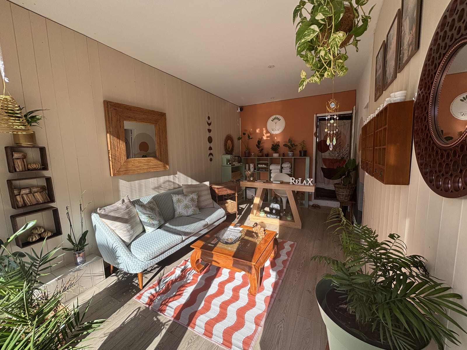 Vue d'ensemble du salon Les Rituels de Toav : espace chaleureux avec plantes, tapis terracotta et coin soin